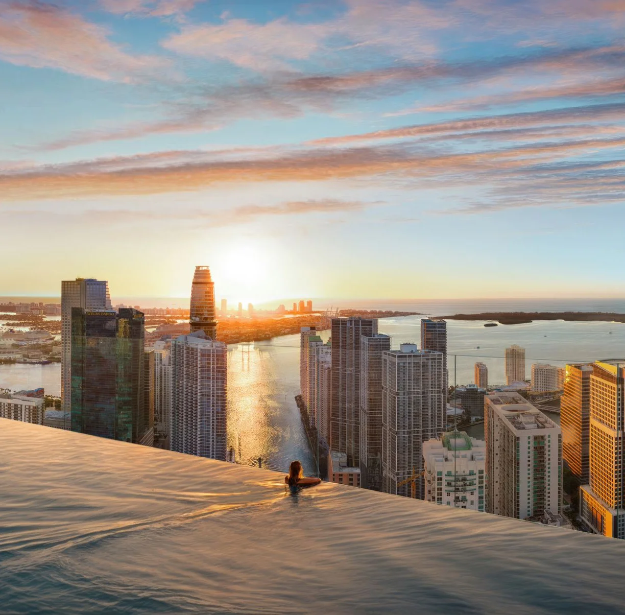 A rooftop infinity pool above the Miami River at sunrise, the Brickell skyline beyond